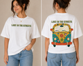 Women wearing white oversized graphic t shirt with floral Lost In The Streets text on front and vibrant hippie van back print